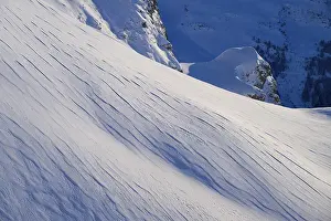 Snow-covered slopes with fine lines under a blue sky