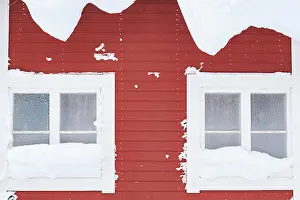 Snow-covered windows, red wooden house