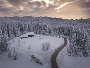 Snow covered winter forest landscape aerial view with pines and mountains in the background