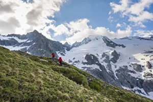 Snow field, hikers in front of snow-covered mountain peaks