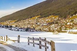 Snowy alpine village in Italy illuminated by sun with mountains in the background
