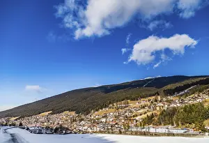 Snowy alpine village in Italy illuminated by sun with mountains in the background