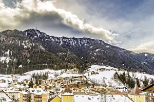 Snowy alpine village in Italy illuminated by sun with mountains in the background