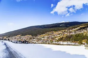 Snowy alpine village in Italy illuminated by sun with mountains in the background