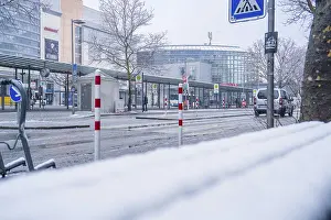 Snowy, empty bus stop in front of a modern building in the city