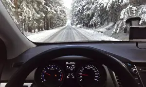 Snowy forest road, view through car windshield