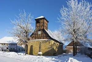Framed Print : Snowy half-timbered church with blue sky and snow-covered trees in the background Framed Print : Snowy half-timbered church with blue sky and snow-covered trees in the background