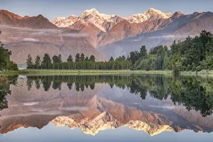 Snowy mountain peaks of Mount Cook and Mount Tasman reflected in Lake Matheson in the evening light