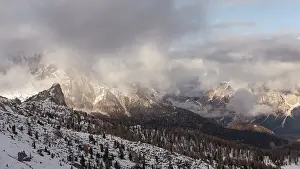 Snowy mountains under a cloudy sky with scattered sunlight