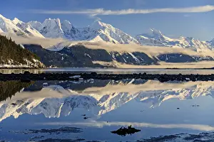 Snowy mountains reflected in fjord
