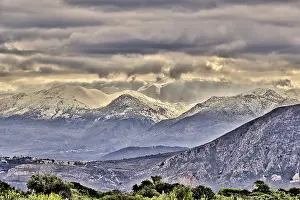 Snowy mountains under threatening grey clouds in a vast landscape with a dramatic atmosphere