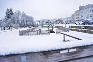 A snowy playground with a view of residential buildings in winter