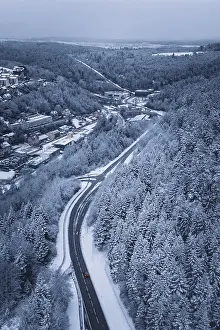 Snowy road through a forest, quiet winter landscape with lonely car
