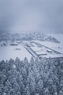 Snowy village on the edge of a forest under cloudy sky
