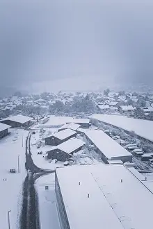 Snowy village landscape with buildings under a cloudy sky