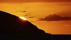 Soft orange light of the sun behind a mountain