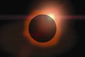 Solar eclipse with orange halo on black sky background
