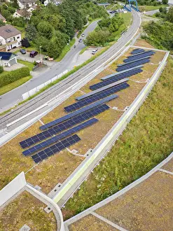 Solar system on a green roof next to railway tracks with urban surroundings