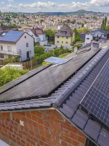 Solar panels on a roof with a view of the city under a sunny sky