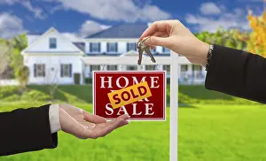 Sold real estate sign and agent handing over keys to new home