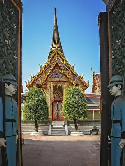 Soldiers sculptures guarding open gates to the Buddhist temple in Bangkok