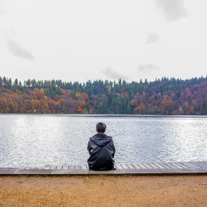 A solitary figure sits on a wooden dock