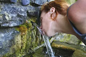 Source of spring water woman drinking in mountain of Pyrenees