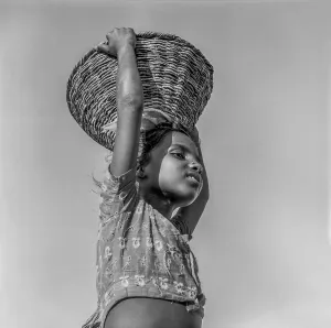 South Asian Indian working girl child lifting basket on head