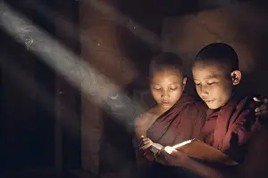 Southeast Asian novice monk reading book inside monastery