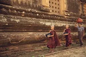 Southeast Asian young Buddhist novice monks walking morning alms in Old Bagan