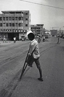 Southern provinces, China, circa 1982: An amputee crosses the road with the help of a crutch