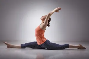 Sporty fit woman doing Hatha yoga asana Hanumanasana (splits)