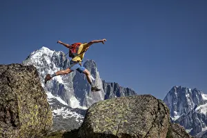 Sporty jump between two rocks against an impressive mountain backdrop
