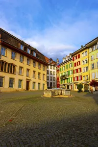 Square in Old Town with House and Water Fountain with Statue Justice