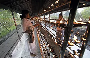 Sri Lankan pilgrims pour oil into candle holders at the Buddhist Temple of the Tooth or Sri Dalada Maligawa