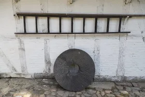 A standing millstone and hanging wooden ladder