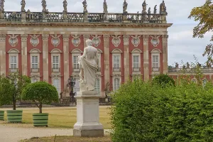 Statue in the foreground, behind a majestic building with a red facade and symmetrical windows