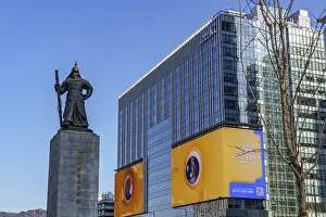 Statue in front of modern buildings and billboards in an urban environment