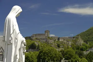 Statue on Rosary Square and the Chateau fort de Lourdes fortress in the Marian pilgrimage town of Lourdes