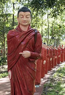 Statues of monks walking behind Buddha
