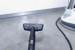 Steam cleaner directed at a gray floor in a modern kitchen