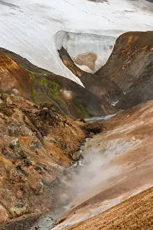 Steaming stream between colourful rhyolite mountains and snowfields