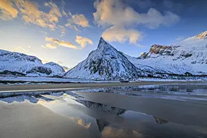 Steep mountain reflected in the water on the beach