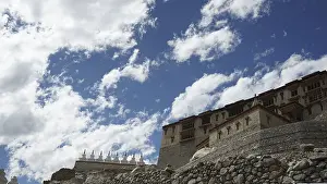 Stone Buddhist monastery building under a dramatic sky full of clouds