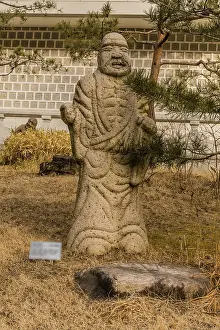 Framed Print : Stone carved statue of Buddhist deity kanakavatsa in front of white wall in garden in South Korea
