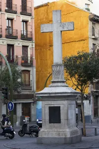 Stone cross made in 1738 against a vivid orange wall at the Plaza de Puerta Cerrada in the old part of Madrid in Spain