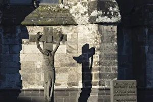 Stone cross with shadow cast, cathedral cemetery near Cologne Cathedral