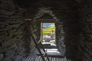 Stone interior of a defence tower with ladder and view of a green valley