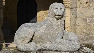 Stone lion statue sits majestically in front of a medieval fortress