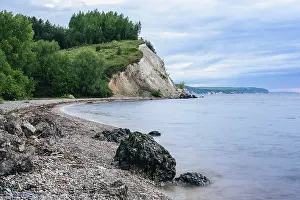 Stone on the riverbank and cliff with birch woodland on background